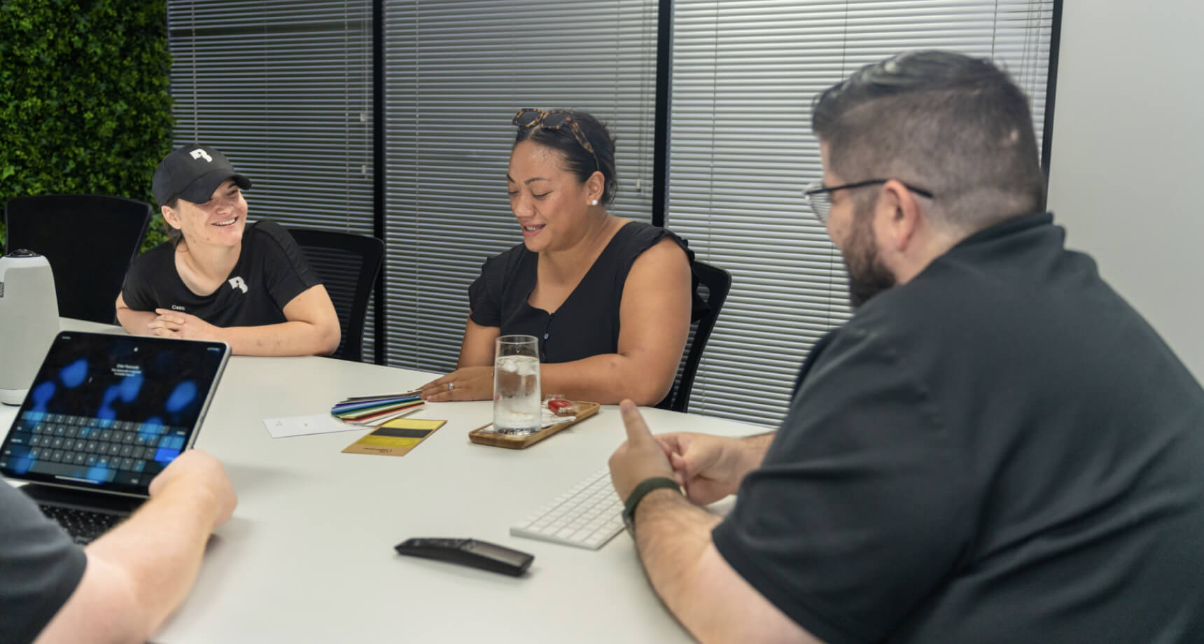 A group of people sitting around a table with laptops