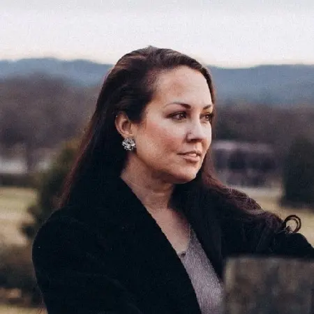 A woman in a black jacket is looking off into the distance
