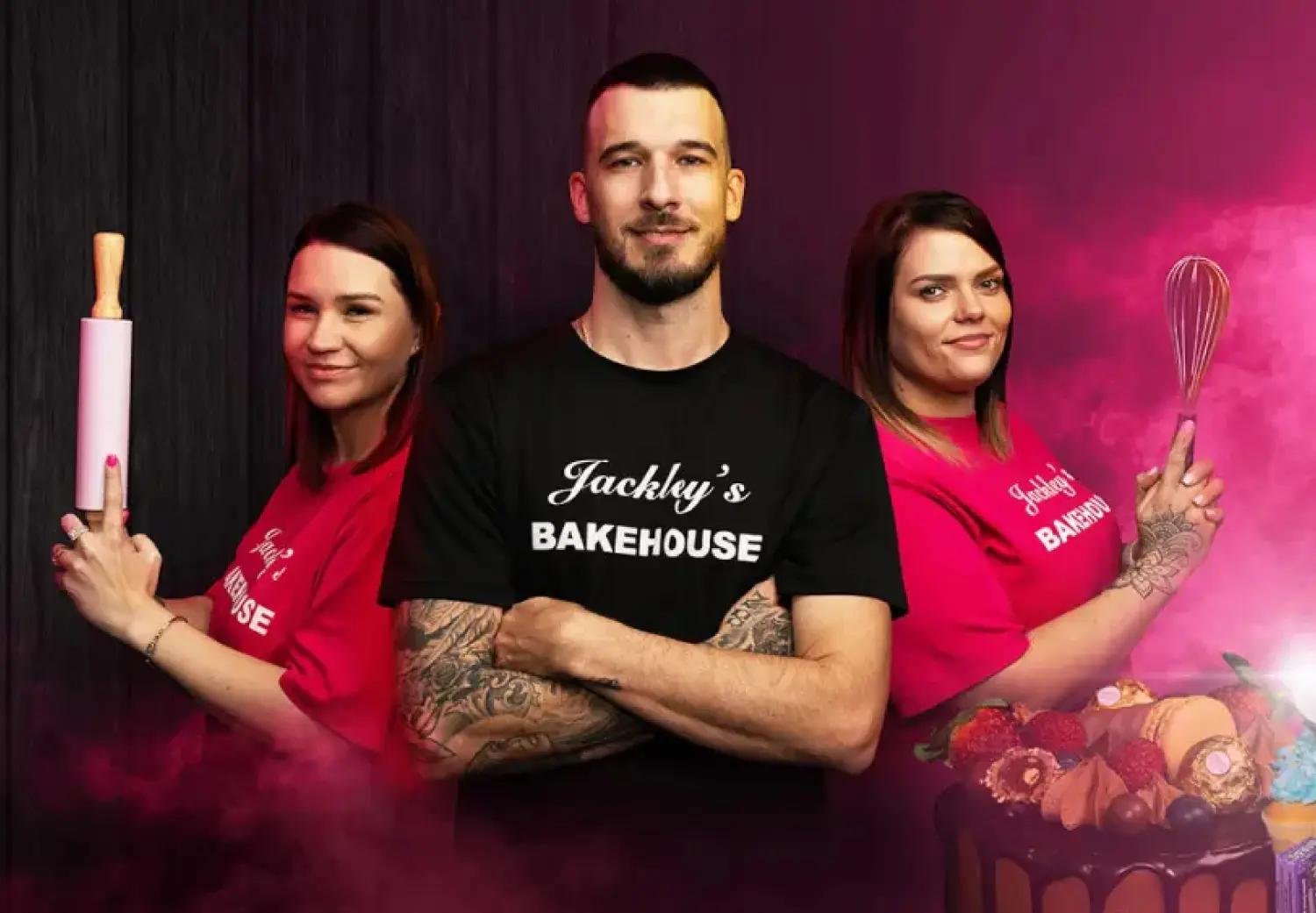 A man and two women in pink shirts holding a whisk