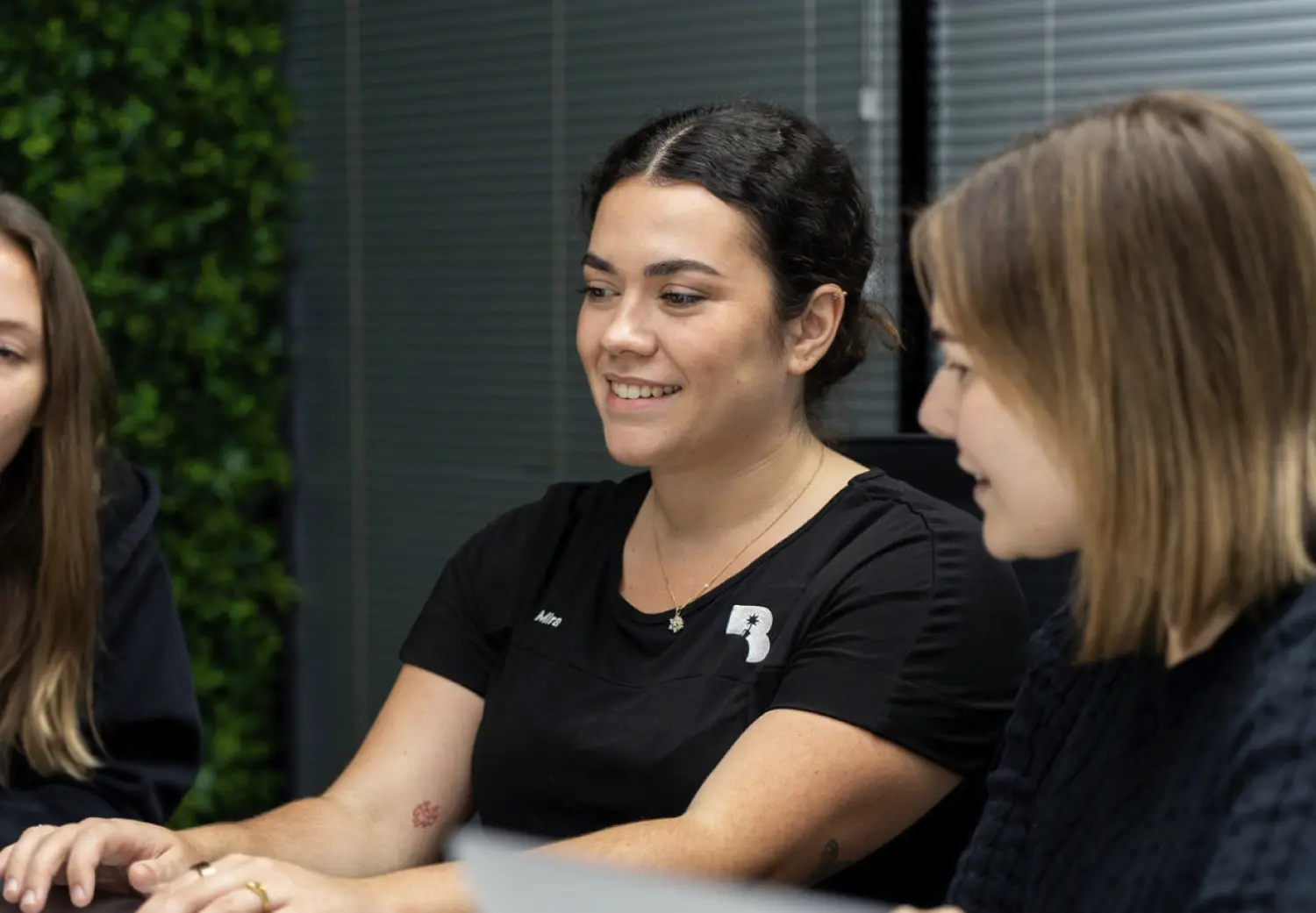 Three women sitting at a table with a laptop