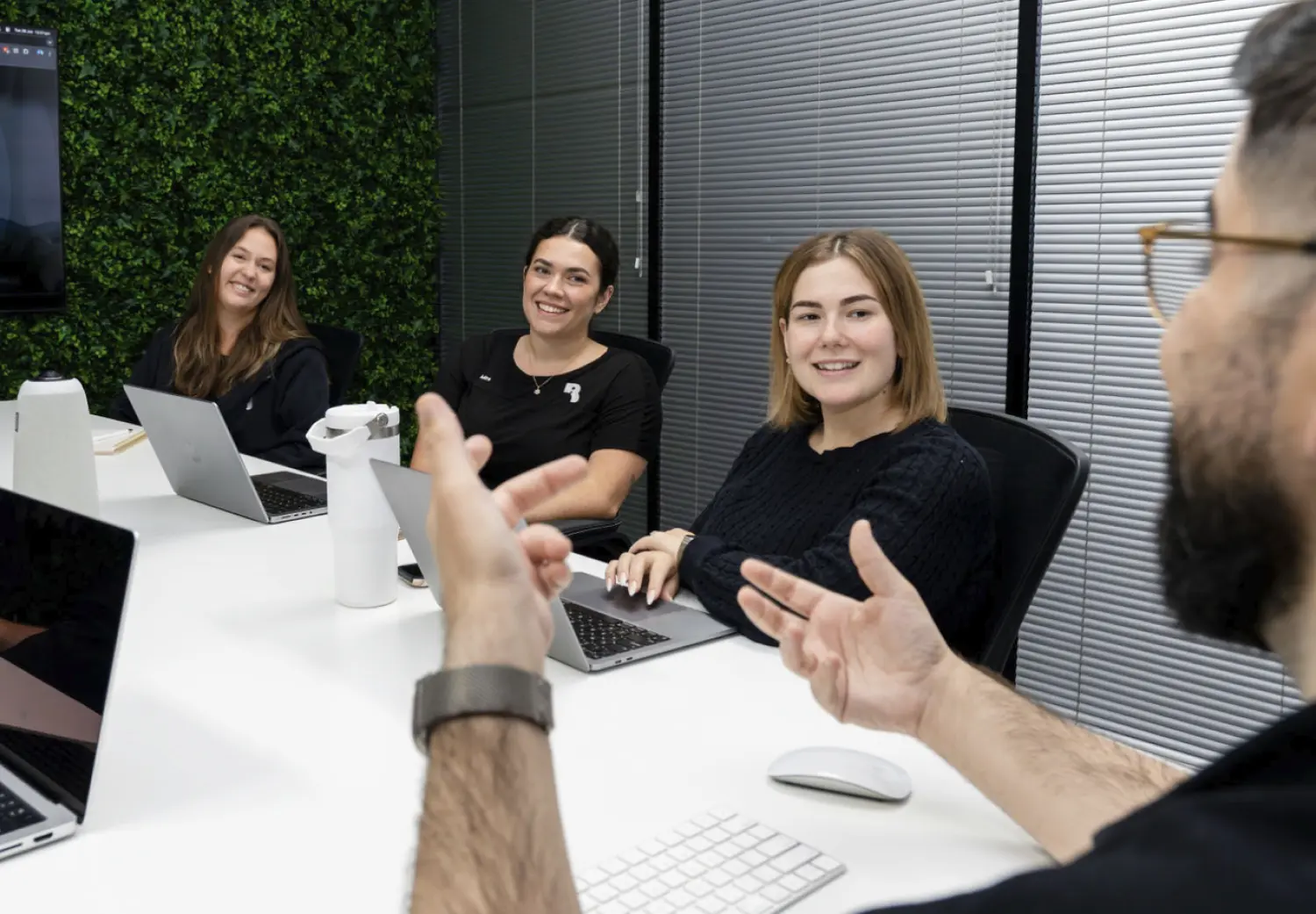 A group of people sitting around a table with laptops