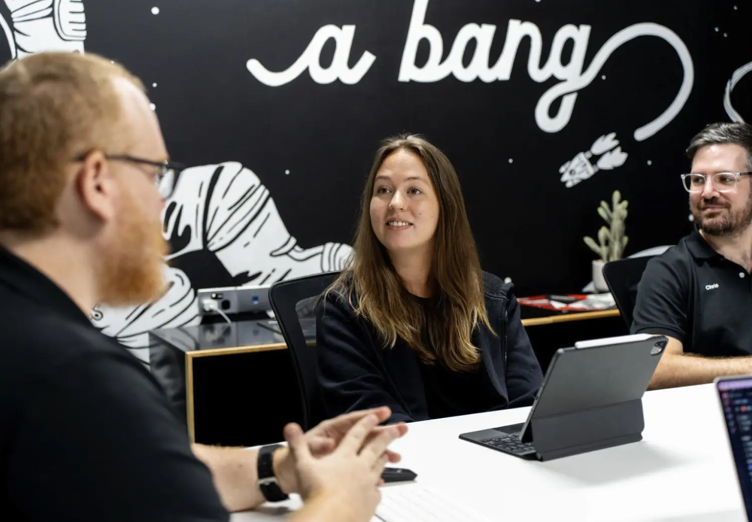 A group of people sitting around a table with laptops