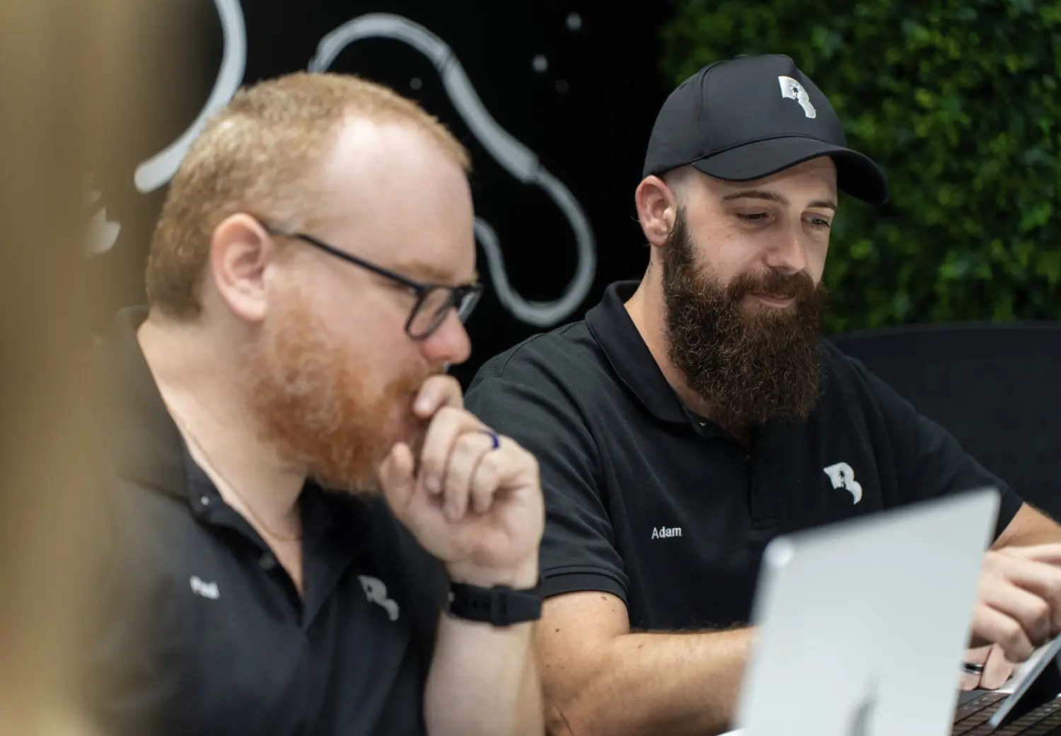 Two men sitting at a table with laptops