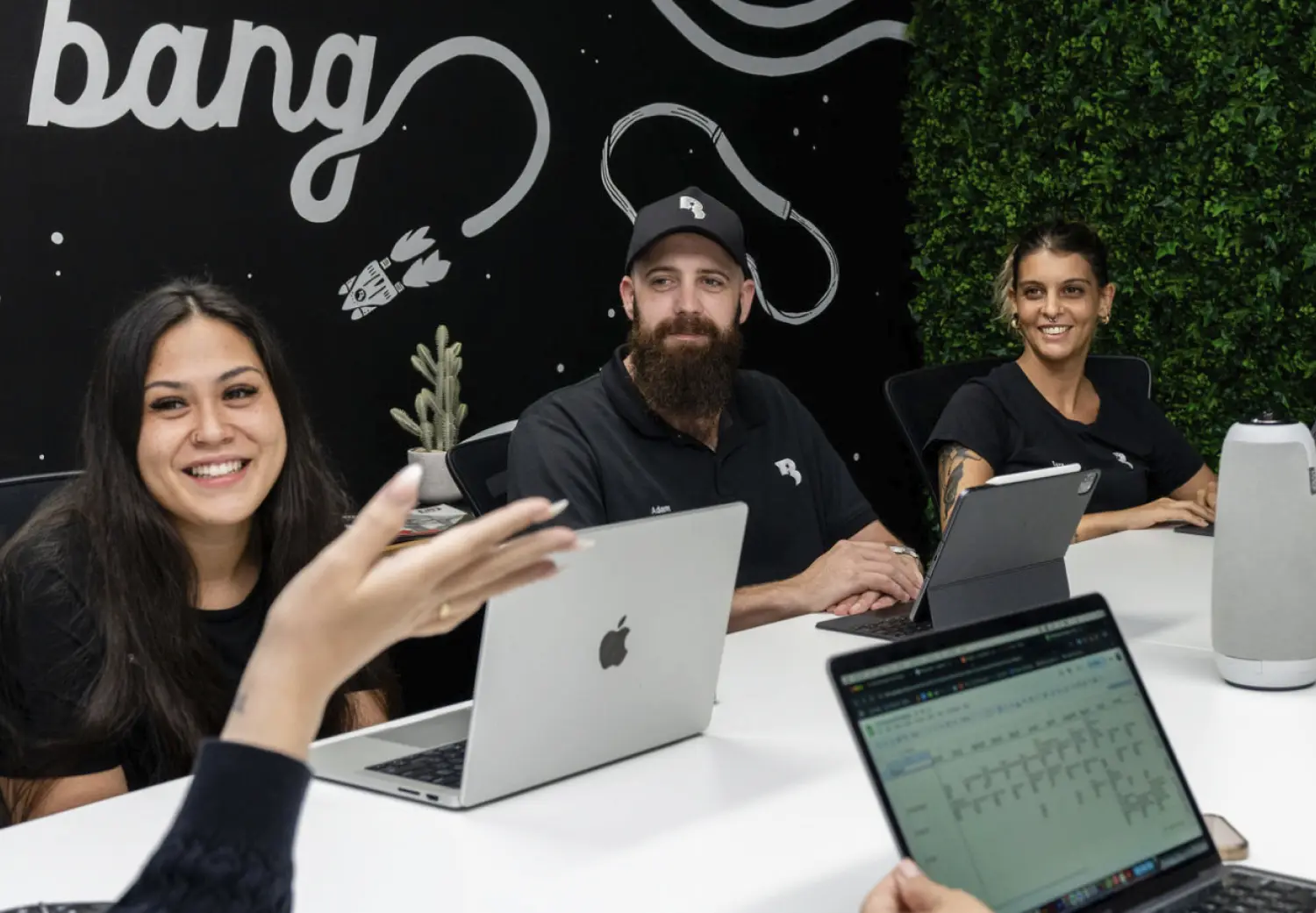 A group of people sitting around a table with laptops