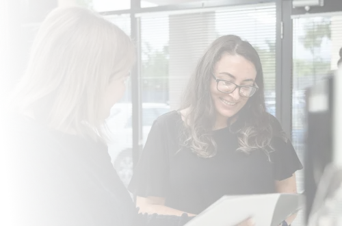 Two women standing in front of a computer screen