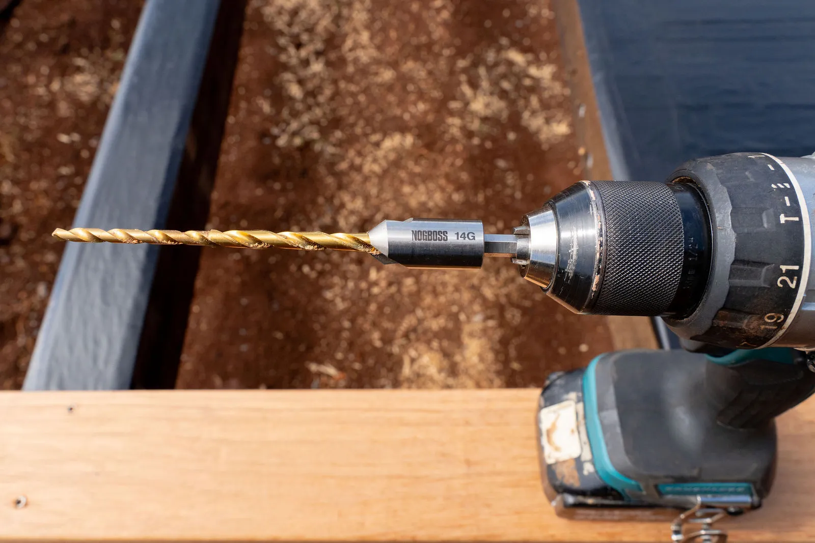 NOGBOSS 14g wood drill and countersink assembly in a drill on a timber deck