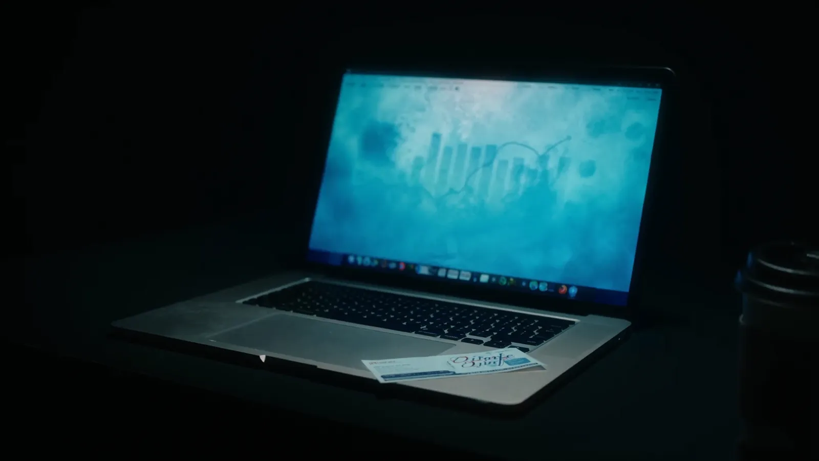 Dark desk scene with a laptop showing advertising campaign graphs beside a notebook and coffee